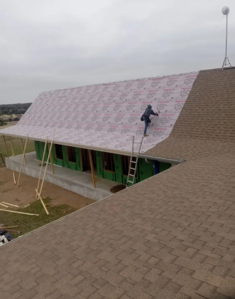 Worker preparing underlayment for a metal roof installation in Cupertino